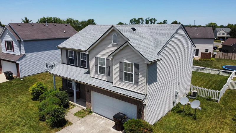 Aerial view of a two-story home with a new light gray architectural shingle roof