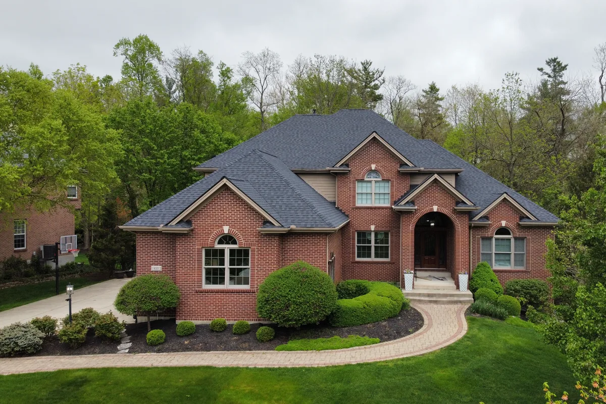 Front view of a brick two-story home with a new charcoal shingle roof