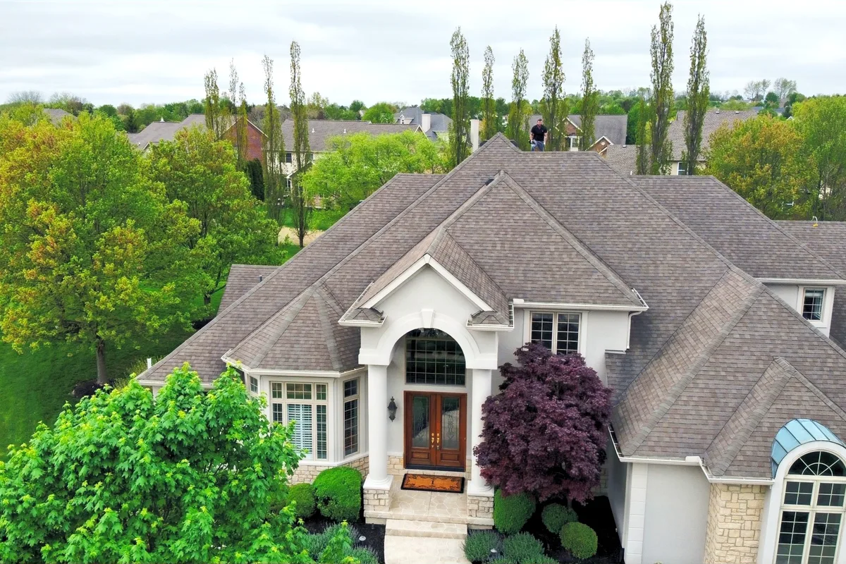 Aerial view of a stone-front home with a new brown architectural shingle roof