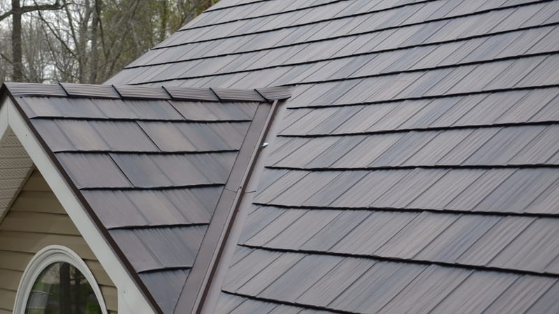 A metal shake roof in weathered brown and grey over a gabled dormer