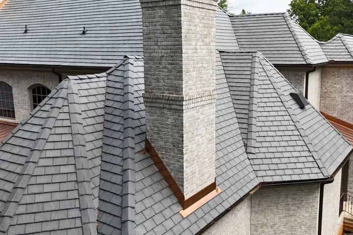 DaVinci composite slate roof in grey with copper flashing around a brick chimney