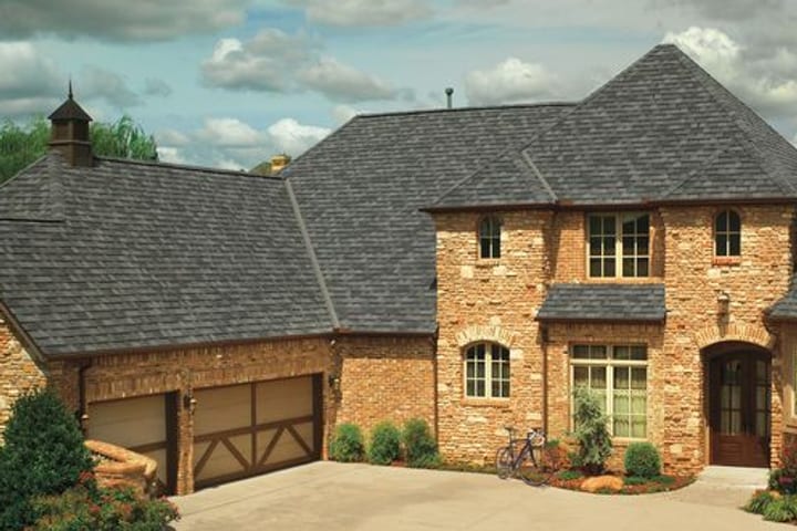 A stone two-storey home with a GAF Camelot designer shingle roof in charcoal