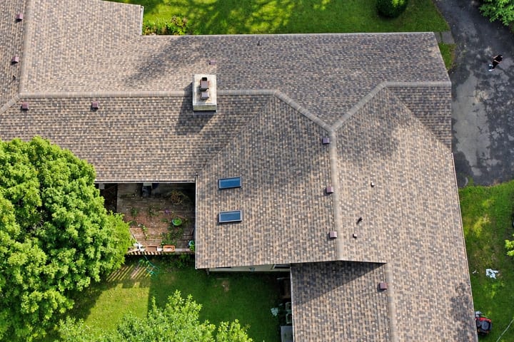 Aerial close-up of a finished GAF architectural shingle roof in brown and charcoal with skylights