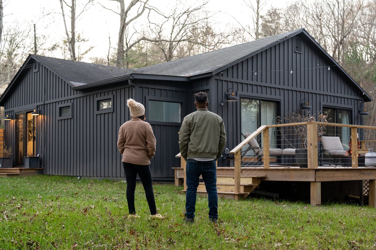 Two homeowners standing in their backyard looking up at the new roof on their home
